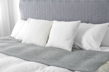 Bed with soft fluffy pillows at home