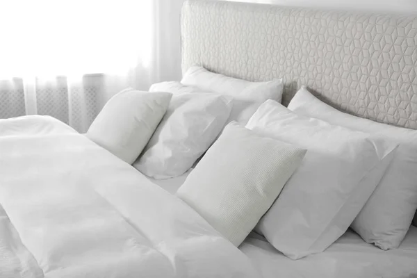 Łóżko z miękkimi puszystymi poduszkami w domu — Zdjęcie stockowe
