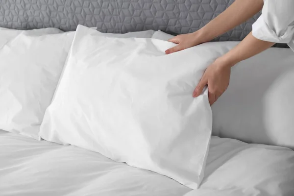 Donna fluffing morbido cuscino in camera da letto, primo piano — Foto Stock