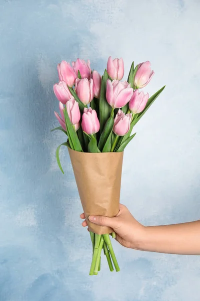 Mujer con hermosos tulipanes rosados de primavera sobre fondo azul claro — Foto de Stock