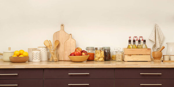 Деревянная столешница с посудой и продуктами возле белой стены. Идея интерьера кухни
