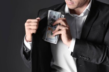 Man putting bribe money into pocket on black background, closeup clipart