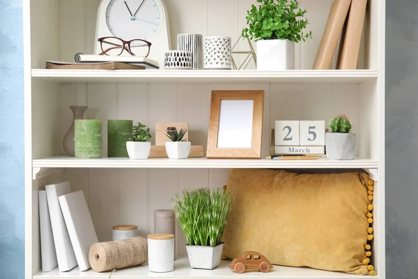 Bitkilerle dolu beyaz raf ünitesi ve farklı dekoratif malzemeler.