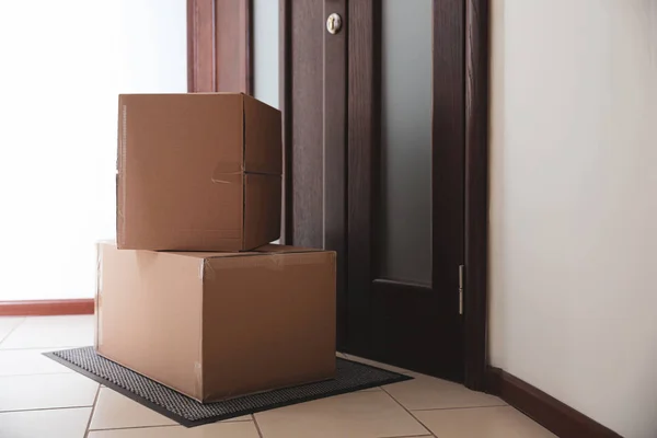 Caixas de papelão no tapete perto da porta. Serviço de entrega de encomendas — Fotografia de Stock