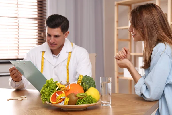 Nutritionist consulting patient at table in clinic — Stock Photo, Image