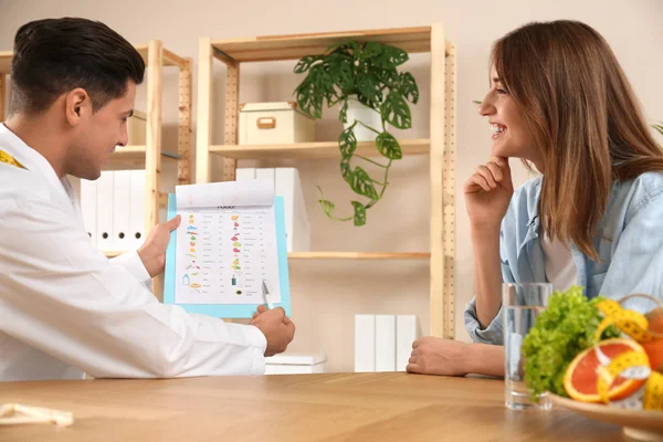 Nutritionist consulting patient at table in clinic — Stock Photo, Image