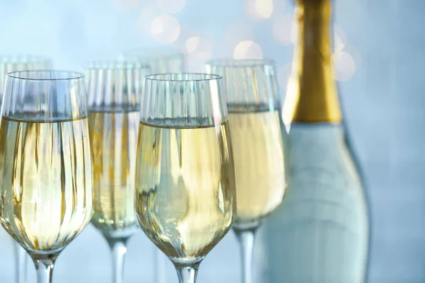 Copos e garrafa de champanhe contra luzes embaçadas, close-up — Fotografia de Stock