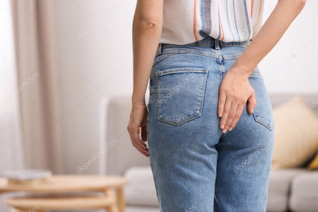 Young woman suffering from hemorrhoid at home, closeup