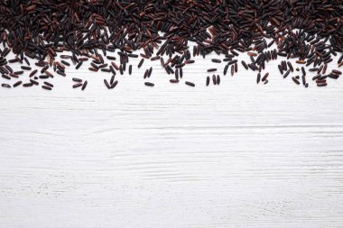 Brown rice on white wooden table, top view