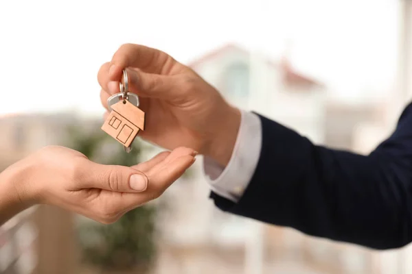 Agent nieruchomości daje klucz z błyskotką do klienta w biurze, c — Zdjęcie stockowe