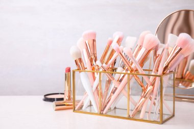 Set of professional makeup brushes in holder on table