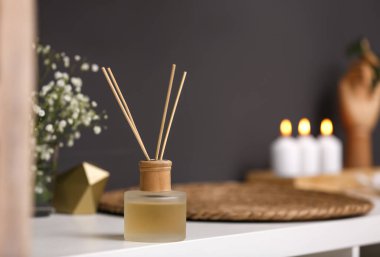 Reed diffuser on white table in modern bathroom