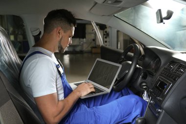 Mechanic with laptop doing car diagnostic at automobile repair s