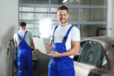 Mechanic with laptop doing car diagnostic at automobile repair shop