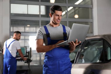 Mechanic with laptop doing car diagnostic at automobile repair 