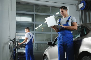 Mechanic with laptop doing car diagnostic at automobile repair shop