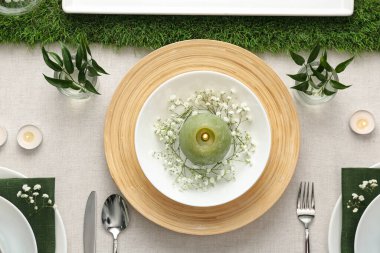 Açık renk kumaşlı yeşil bitkilerle süslü zarif bir masa.