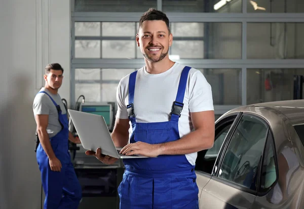 Mechanica met laptop doet auto kenmerkend bij auto reparatie s — Stockfoto
