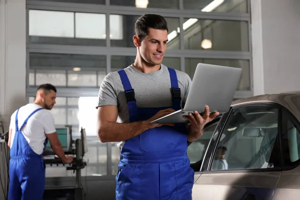 Mechanica met laptop doet auto kenmerkend bij auto reparatie — Stockfoto