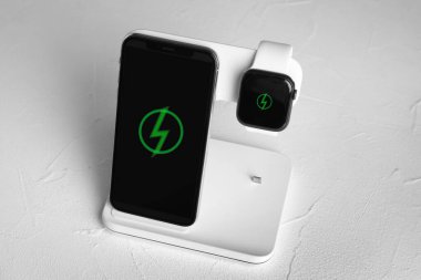 Mobile phone and smartwatch charging with wireless pad on white 