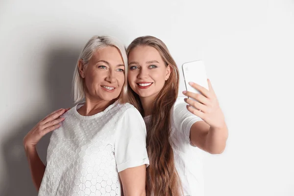 Mère et fille heureuses prenant selfie sur fond blanc — Photo