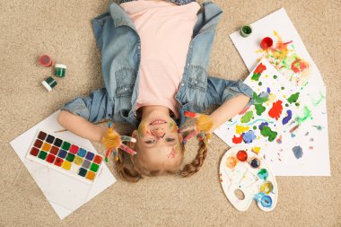 Cute little child with painted face and palms on floor, top view