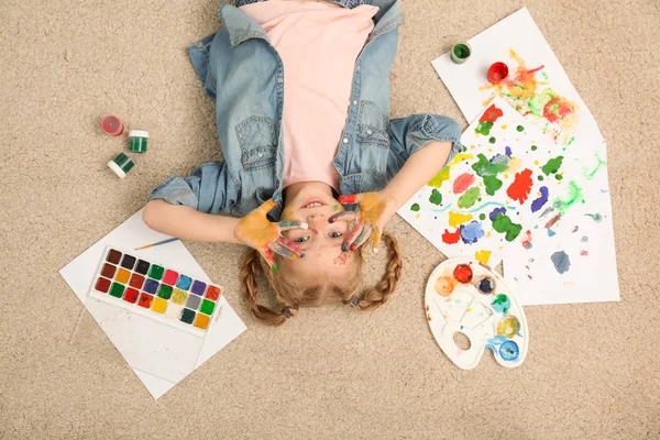 Cute little child with painted face and palms on floor, top view — Stock Photo, Image
