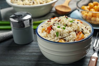 Delicious rice pilaf with chicken on black wooden table