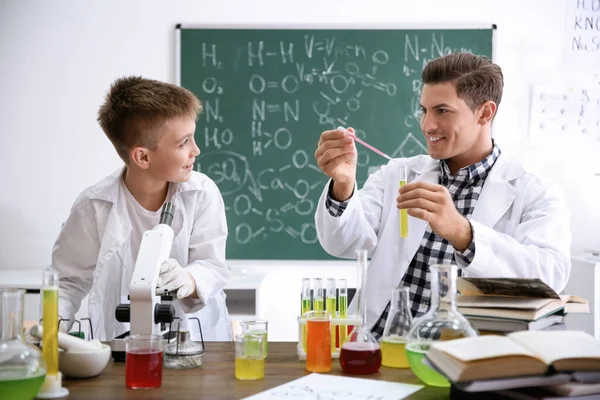 Professor com aluno fazendo experiência na mesa em aula de química — Fotografia de Stock