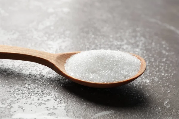 Spoon of white sugar on marble table, closeup — Stockfoto