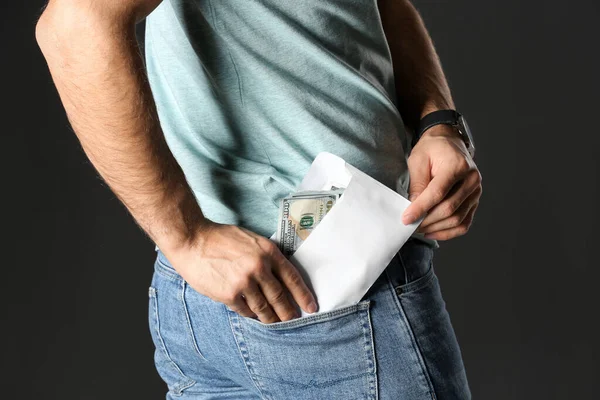 Man putting bribe money into pocket on black background, closeup