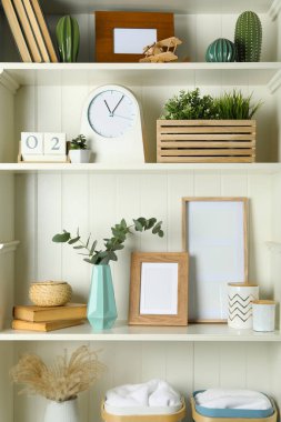 White shelving unit with photo frames and different decorative elements