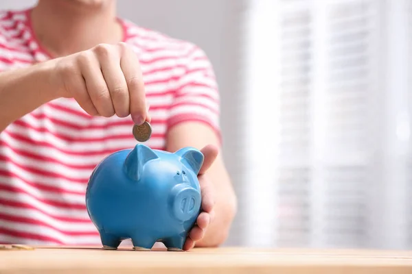 Een man die geld in spaarpot stopt aan een houten tafel, close-up. Ruimte — Stockfoto