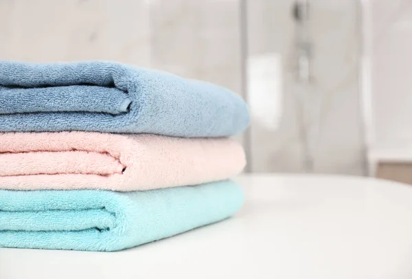 Stack of fresh towels on white table in bathroom, closeup. Space — Stock Photo, Image