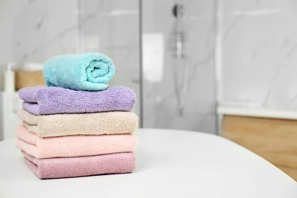 Montón de toallas frescas en la mesa blanca en el baño. Espacio para texto —  Fotos de Stock