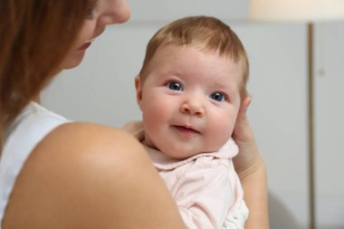 Young woman with her little baby resting after breast feeding at home, closeup