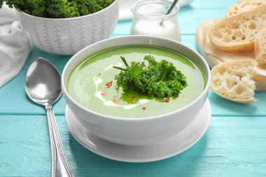 Açık mavi ahşap masada servis edilen lezzetli lahana çorbası.