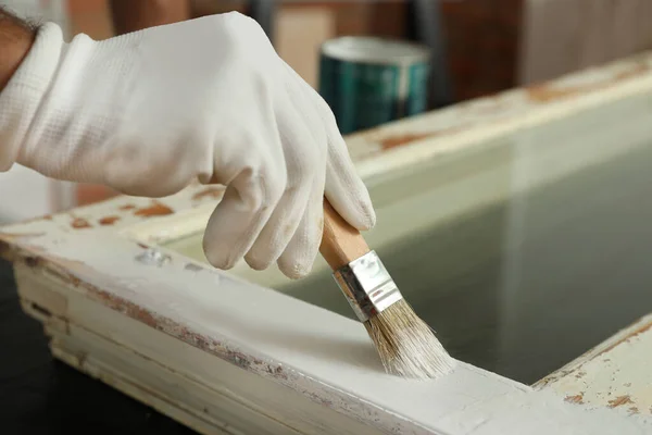 Repairman painting old window at table indoors, closeup — Stock Photo, Image