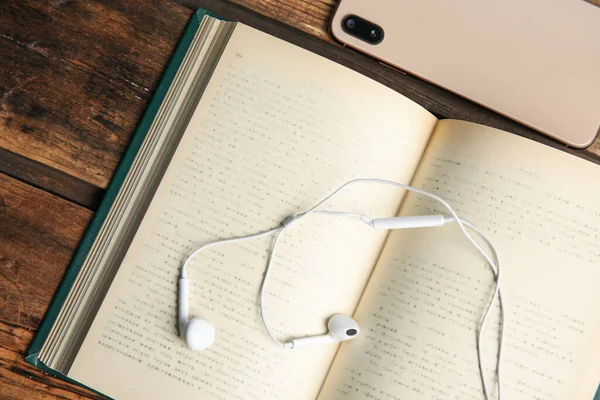 Βιβλίο, ακουστικά και smartphone σε ξύλινο τραπέζι, closeup — Φωτογραφία Αρχείου