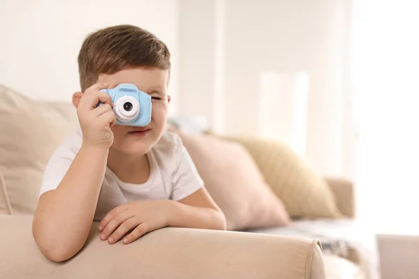 Liten fotograf tar bild med leksak kamera på soffan hos ho — Stockfoto