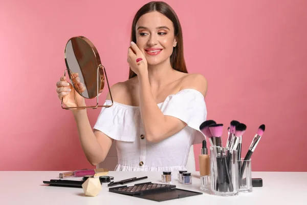 Beauty blogger with mirror on pink background