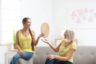 Anne ve yetişkin kızı evde birlikte vakit geçiriyorlar.