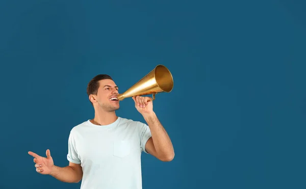 Bonito homem com megafone no fundo azul — Fotografia de Stock