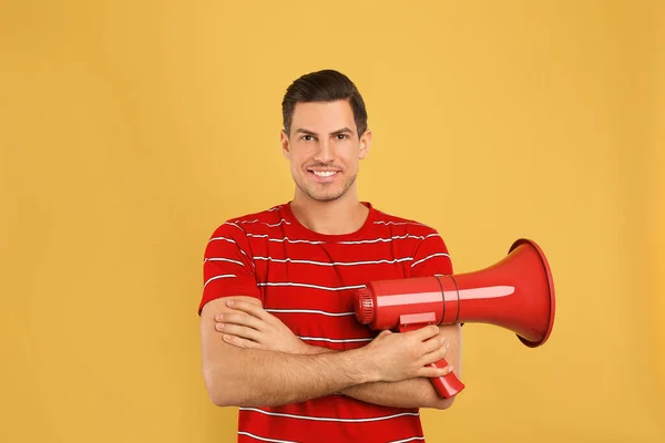 Hombre guapo con megáfono sobre fondo amarillo — Foto de Stock