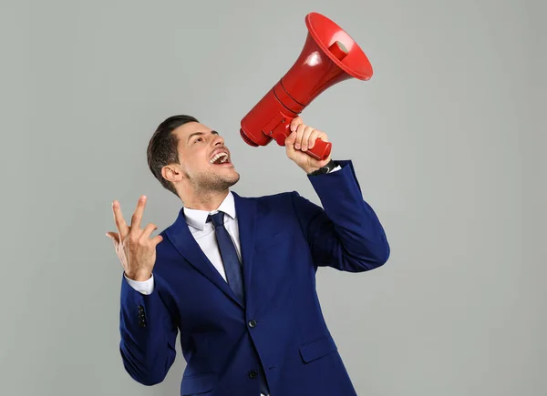 Bonito homem com megafone em fundo cinza — Fotografia de Stock