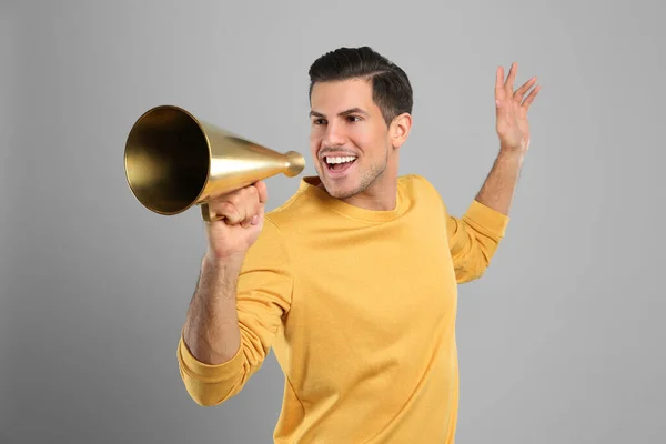 Hombre guapo con megáfono sobre fondo gris — Foto de Stock