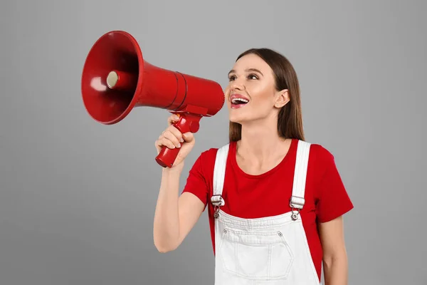 Jovem mulher com megafone no fundo cinza claro — Fotografia de Stock