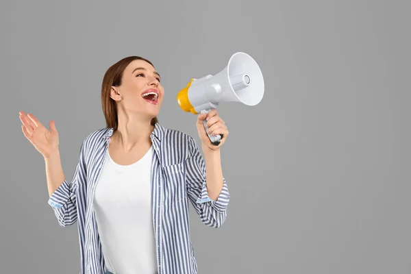 Emocionální mladá žena s megafonem na světle šedém pozadí. S — Stock fotografie
