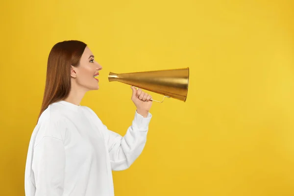 Mladá žena s vintage megaphone na žlutém pozadí — Stock fotografie