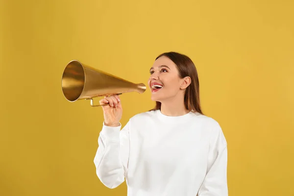 Mladá žena s vintage megaphone na žlutém pozadí — Stock fotografie